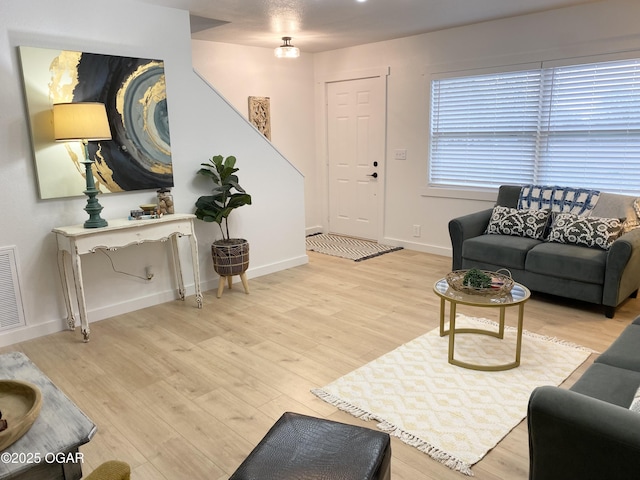 living area with visible vents, baseboards, and wood finished floors