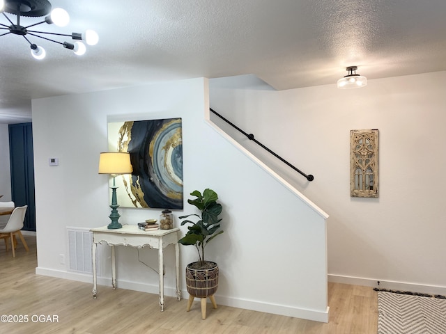 staircase with baseboards, a textured ceiling, visible vents, and wood finished floors