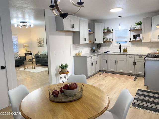 kitchen featuring open shelves, light wood-type flooring, and a sink