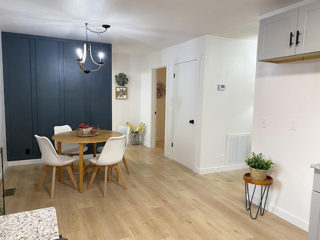 dining room with baseboards, visible vents, a notable chandelier, and light wood finished floors