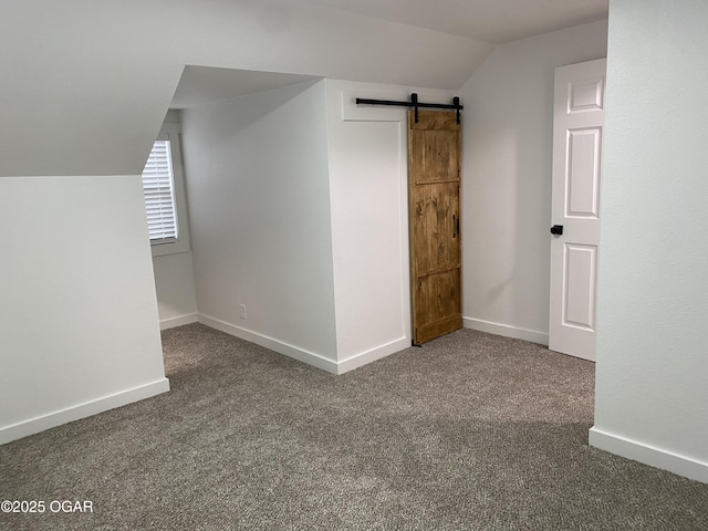 additional living space featuring vaulted ceiling, a barn door, carpet flooring, and baseboards