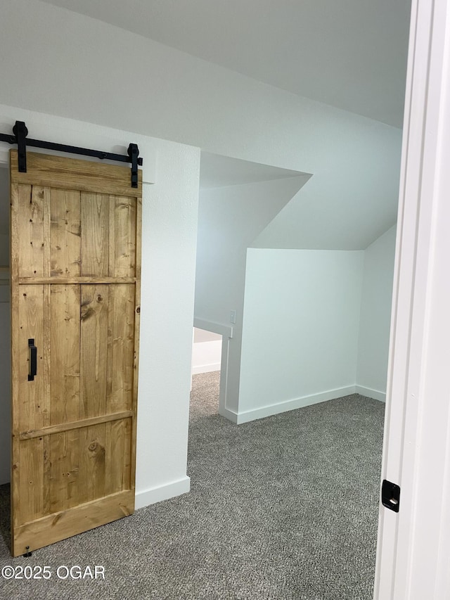 additional living space featuring vaulted ceiling, a barn door, and carpet flooring