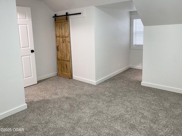 bonus room with lofted ceiling, a barn door, baseboards, and carpet flooring