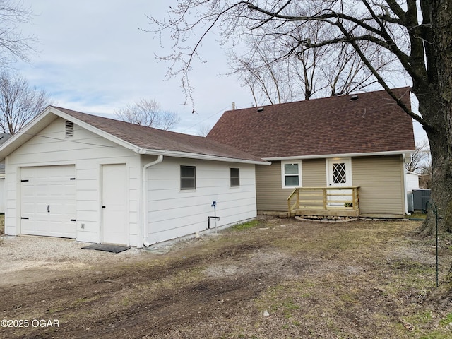 back of house featuring a shingled roof, cooling unit, and dirt driveway