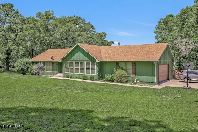 view of front of property with an attached garage, roof with shingles, board and batten siding, and a front yard