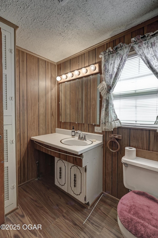 half bathroom with wood walls, toilet, and wood finished floors