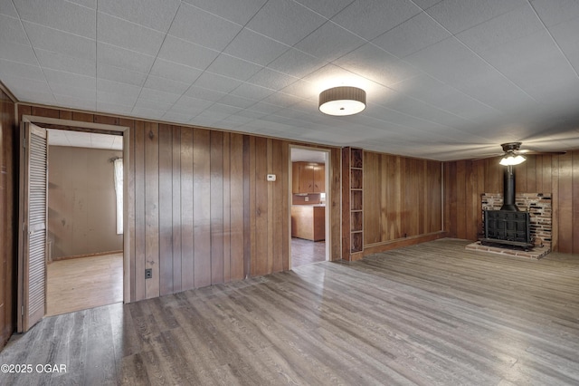 unfurnished living room with a wood stove, wood walls, and wood finished floors