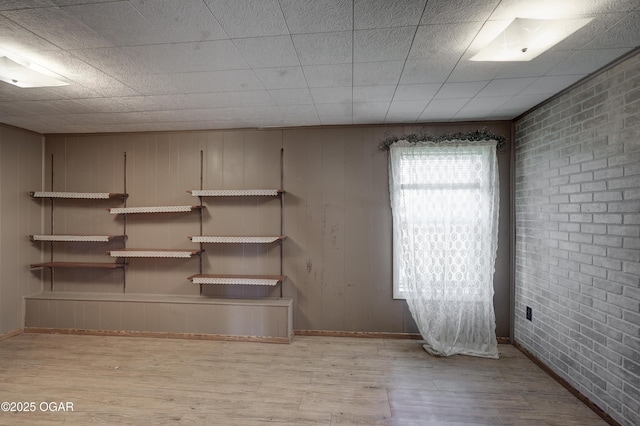 basement featuring brick wall and wood finished floors