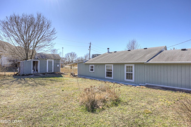 rear view of property featuring a lawn, an outdoor structure, and a shed