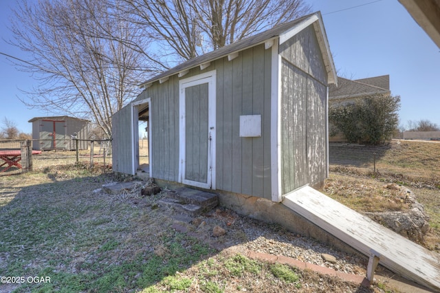 view of outbuilding featuring fence and an outbuilding