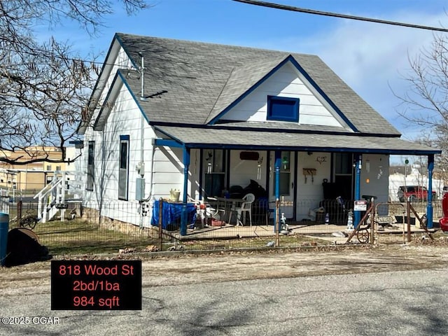 view of front of home with a fenced front yard, roof with shingles, and a porch