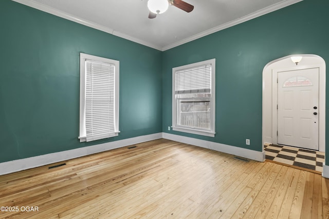 unfurnished room featuring visible vents, baseboards, ceiling fan, wood finished floors, and crown molding