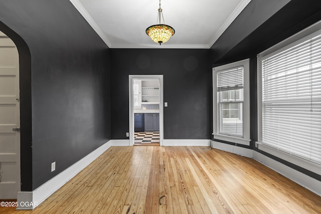 interior space featuring arched walkways, baseboards, hardwood / wood-style flooring, and crown molding