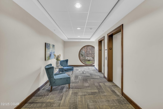 corridor featuring recessed lighting, carpet flooring, baseboards, a tray ceiling, and elevator