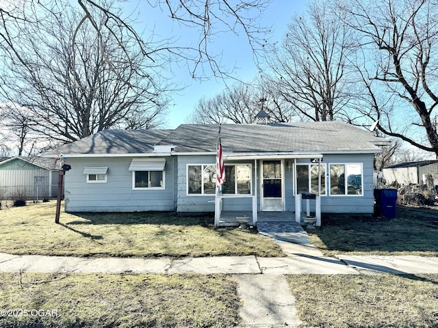 ranch-style home featuring covered porch, a front lawn, and a chimney