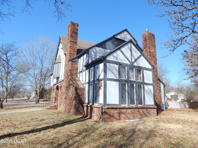 view of home's exterior with a chimney, a lawn, and brick siding