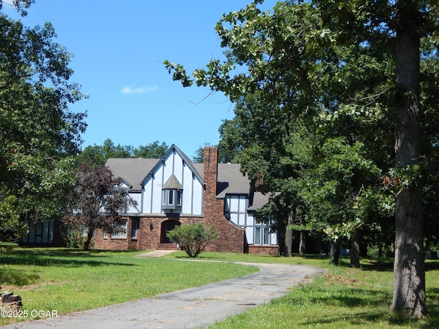 4415 Mcclelland Park Rd, Joplin, MO 64804 - tudor-style house featuring a front lawn, a chimney, brick siding, and stucco siding