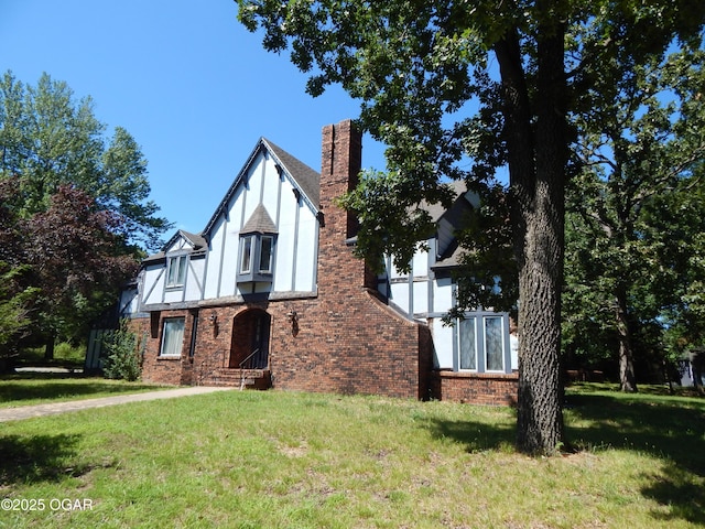 4415 Mcclelland Park Rd, Joplin, MO 64804 - english style home featuring a front yard, a chimney, brick siding, and stucco siding