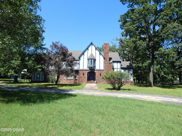 4415 Mcclelland Park Rd, Joplin, MO 64804 - tudor-style house with a front yard, stucco siding, a chimney, and brick siding