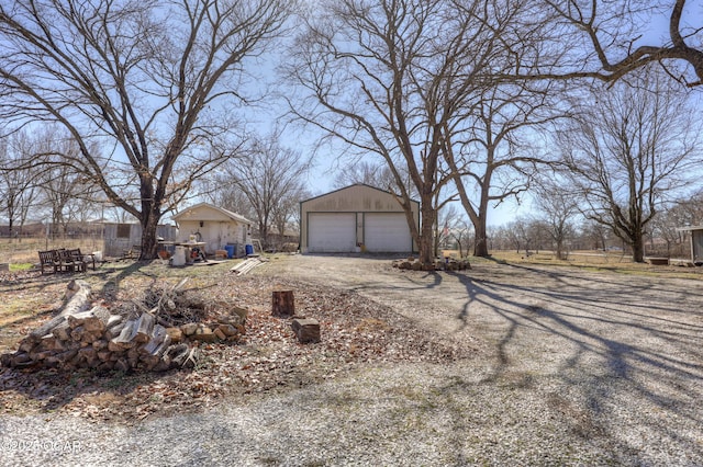 view of yard with an outbuilding, dirt driveway, and a detached garage