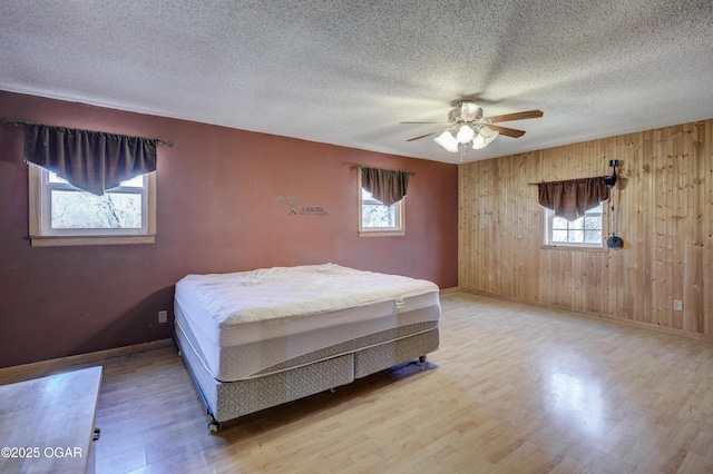 bedroom featuring light wood-style flooring, multiple windows, and a textured ceiling