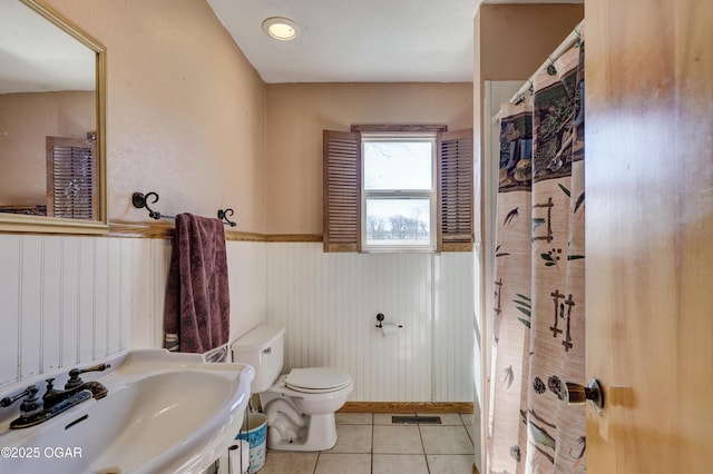 bathroom with toilet, a shower with shower curtain, a sink, visible vents, and tile patterned floors