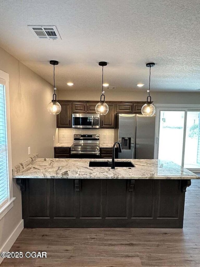 kitchen with appliances with stainless steel finishes, dark wood-style flooring, visible vents, and a sink