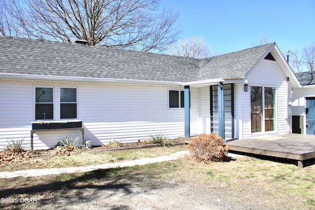 rear view of house featuring a deck and roof with shingles