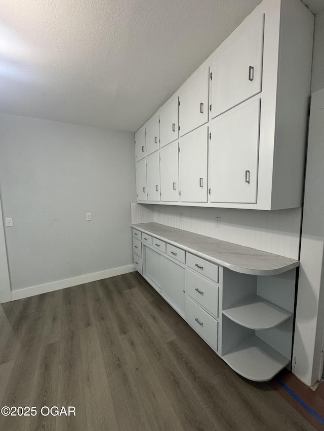 unfurnished office with a textured ceiling, baseboards, and dark wood-style flooring