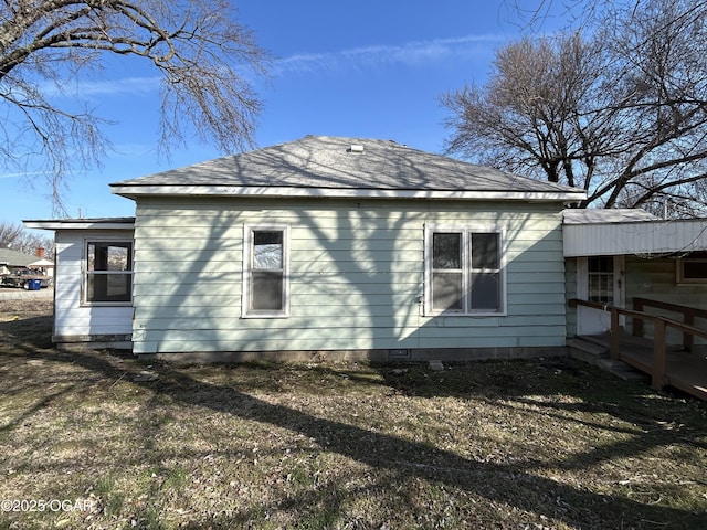 view of side of property with crawl space and a shingled roof