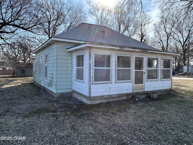 back of house featuring roof with shingles