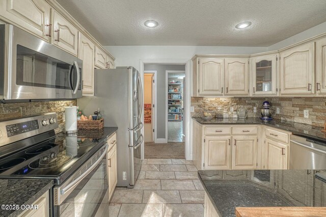 107 Oak Leaf Ter, Joplin, MO 64804 - kitchen featuring stainless steel appliances, dark stone countertops, a textured ceiling, and decorative backsplash