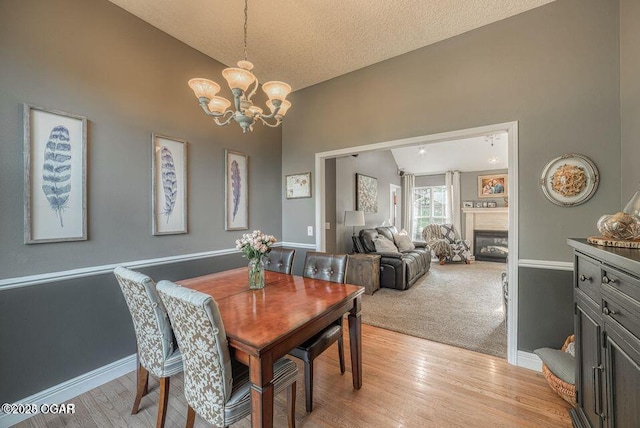 107 Oak Leaf Ter, Joplin, MO 64804 - dining room featuring a glass covered fireplace, vaulted ceiling, light wood finished floors, and an inviting chandelier