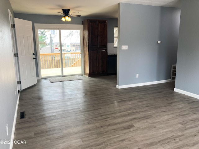 unfurnished living room with a ceiling fan, visible vents, baseboards, and wood finished floors