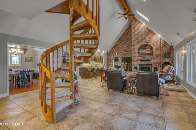 tiled living area with beamed ceiling, stairs, a brick fireplace, high vaulted ceiling, and ceiling fan with notable chandelier