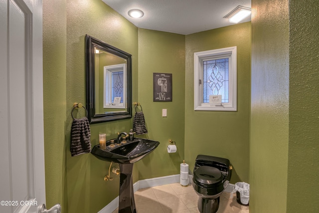 half bathroom with baseboards, toilet, and tile patterned floors