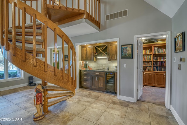 staircase with indoor wet bar, wine cooler, visible vents, and baseboards