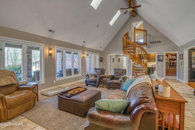 living area featuring a skylight, visible vents, stairway, high vaulted ceiling, and baseboards