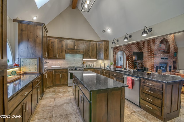 kitchen with a center island, a skylight, stainless steel appliances, tasteful backsplash, and a peninsula