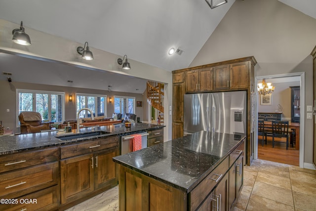 kitchen with a wealth of natural light, dark stone countertops, appliances with stainless steel finishes, and a sink