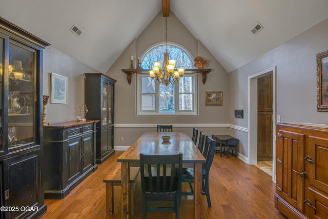 dining room with beam ceiling, visible vents, light wood-style flooring, and an inviting chandelier