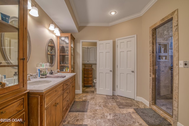 bathroom with a sink, baseboards, ornamental molding, tiled shower, and double vanity