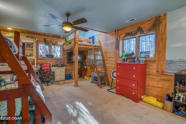 carpeted bedroom with visible vents, wooden walls, and multiple windows