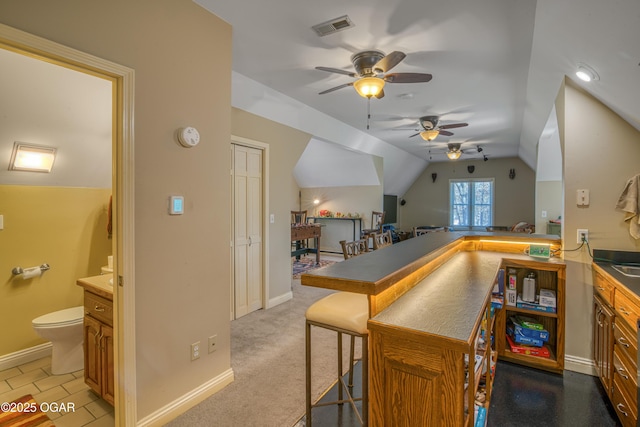 kitchen featuring lofted ceiling, carpet floors, visible vents, and baseboards