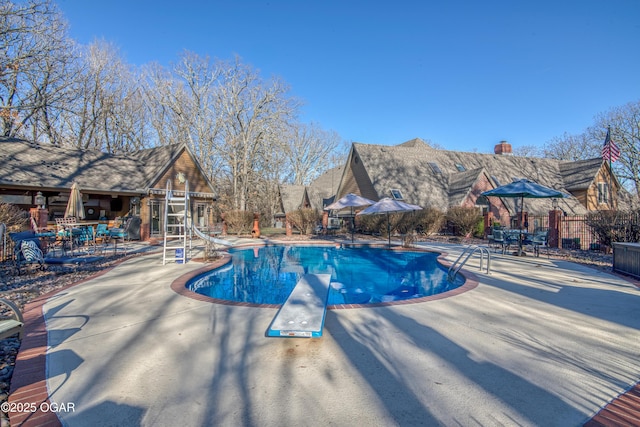 view of swimming pool with a fenced in pool, an outbuilding, a water slide, and a patio