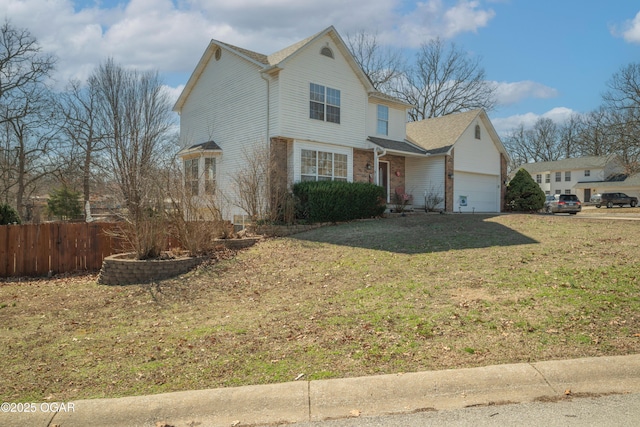 traditional home with brick siding, a front yard, fence, and a garage