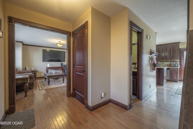 corridor featuring baseboards, a textured ceiling, and hardwood / wood-style flooring