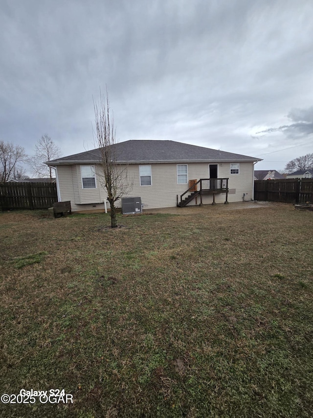 rear view of property with a yard, central AC unit, and fence