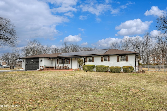 view of front of house featuring brick siding, roof mounted solar panels, fence, a garage, and a front lawn