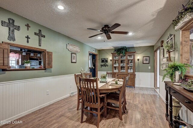 dining room with a wainscoted wall, a textured ceiling, and wood finished floors